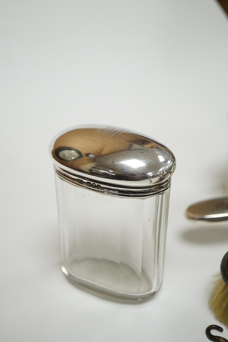 A George V seven piece silver mounted toilet set by Charles Henry Dumenil, comprising a hand mirror, four brushes, a glass toilet jar and button hook, London, 1911/12 & 18, together with one other silver mounted toilet j